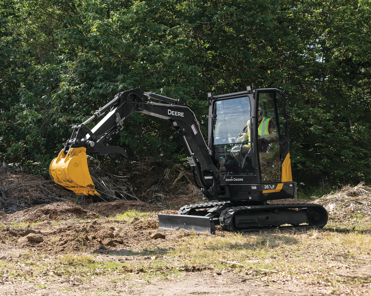 John Deere 26 P-Tier compact excavator working beside a wooded area
