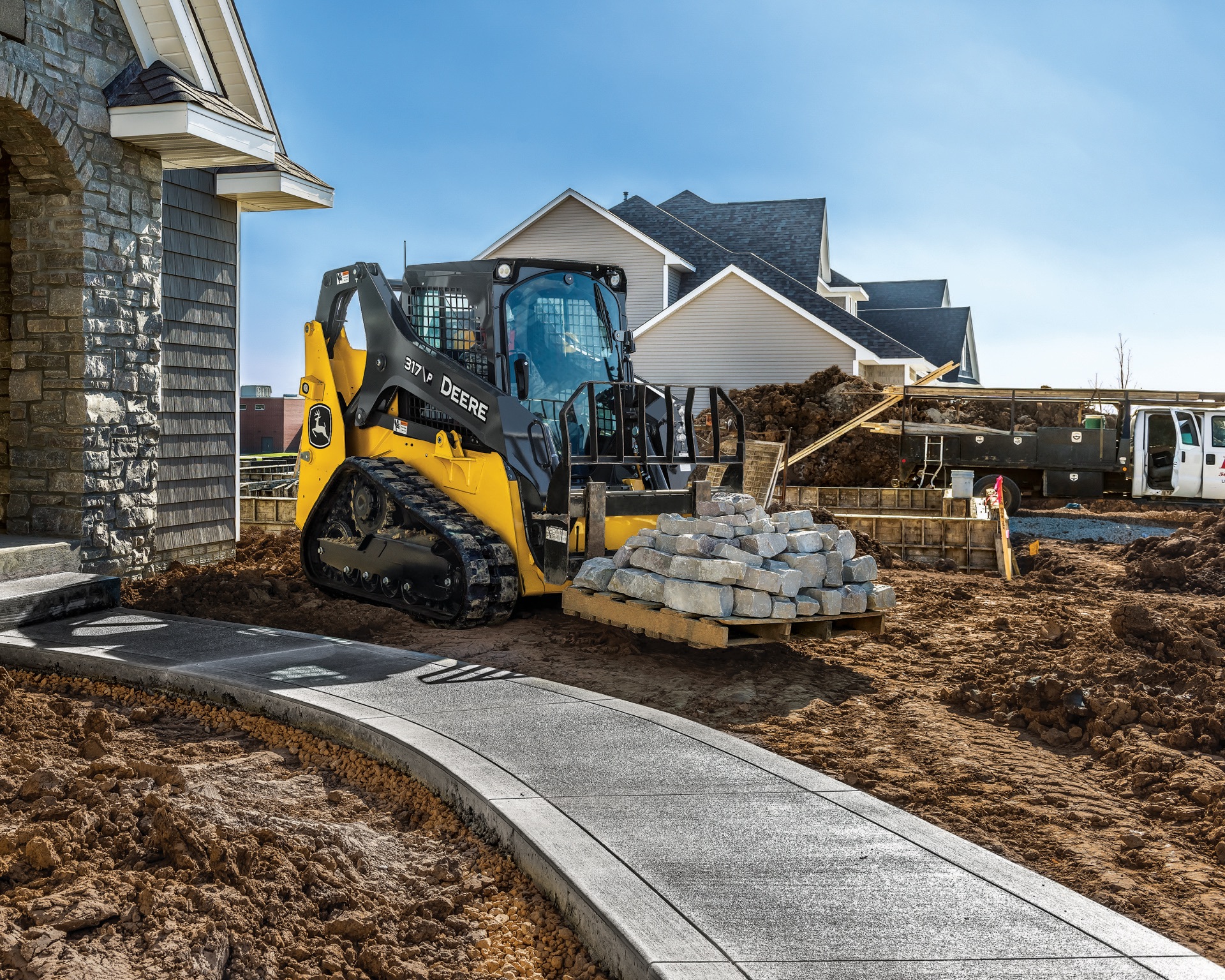 John Deere 317 P compact track loader carrying landscaping stone